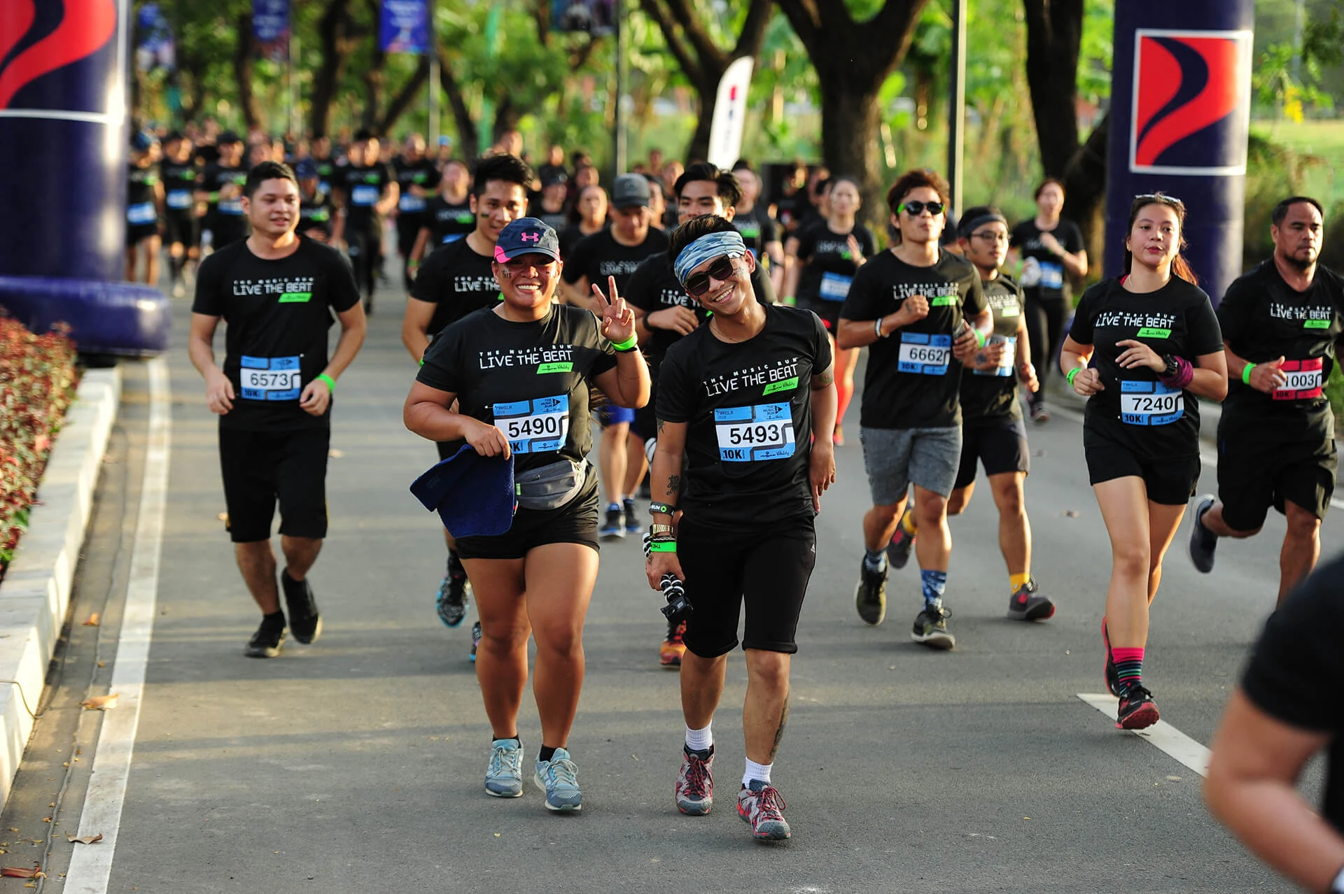 Music Run Manila participants running together on a tree-lined course